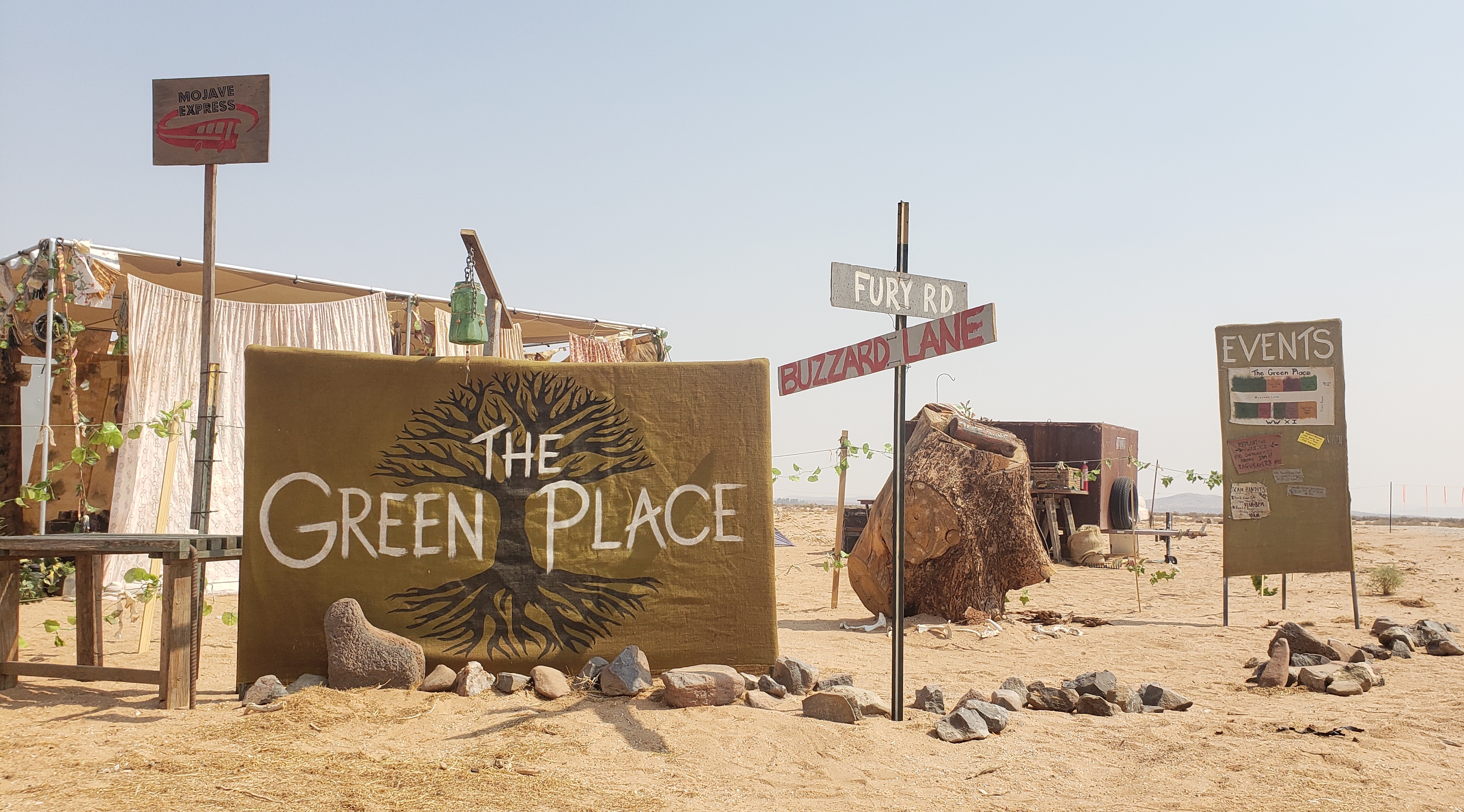 The Green Place entrance sign nestled between our Mojave Express stop, the Tree Thing altar, and our events sign in 2021